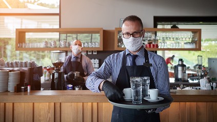 Ein Kellner mit Mundschutz