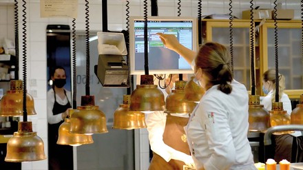 Junge Küchenkraft erhält die Bestellung auf dem gastronovi Küchenmonitor