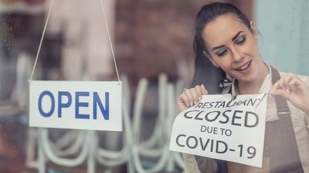 Frau entfernt „Geschlossen wegen Corona“-Schild von Restauranttür