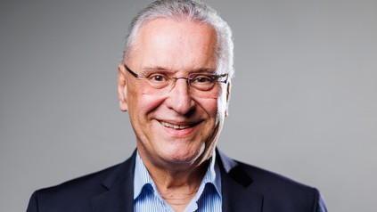 Joachim Herrmann vor grauem Hintergrund.