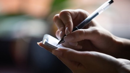 Frau schreibt auf einem Notizblock