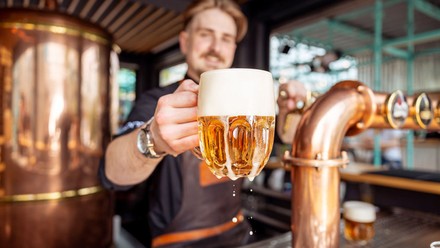 Ein Mann hebt ein Bierseidel in die Kamera.