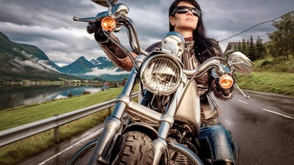Eine Frau fährt mit einem Motorrad durch eine Berglandschaft