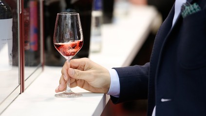 Nahaufnahme eines Mannes, der ein Glas Rotwein auf der Getränkemesse ProWein verkostet