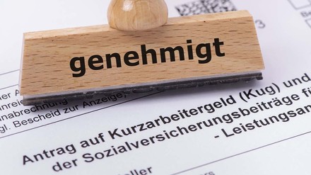 Antrag auf Kurzarbeit und ein Stempel mit der Aufschrift „Genehmigt“
