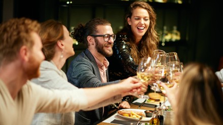 Freunde sitzen am Tisch und stoßen an