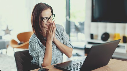 Die Freude bei dieser jungen Frau ist groß: sie sitzt mit breitem Grinsen vor ihrem Laptop.