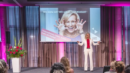 Eine Frau steht auf der Bühne und hält einen Vortrag.