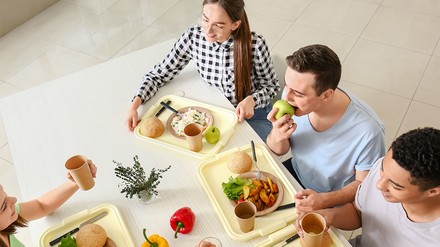 Studenten kommen beim Mittagessen in der Mensa zusammen.