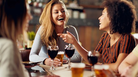 Drei Frauen sitzen an einem Tisch im Restaurant und unterhalten sich.