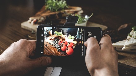 Eine Person fotografiert schön angerichtetes Esse mit dem Smartphone