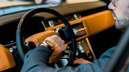 Fahrer schaut im Auto auf seine Armbanduhr