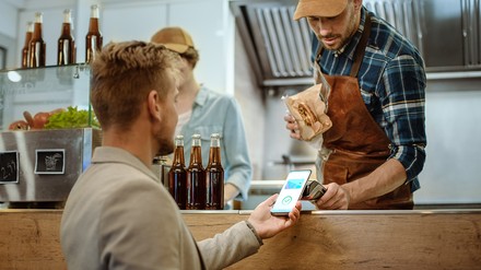 Ein junger Mann zahlt via App an einem Foodtruck.
