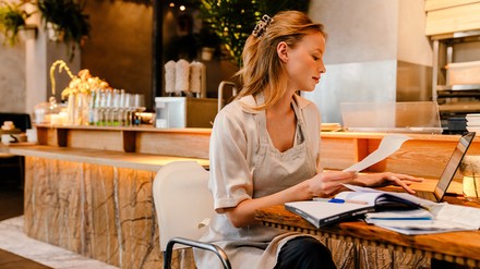 Eine Gastronomin sitzt vor ihrem PC und geht die Abrechnung durch
