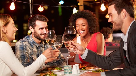 Eine Gruppe von Freunden sitzt im Außenbereich eines Restaurants zusammen und diniert.