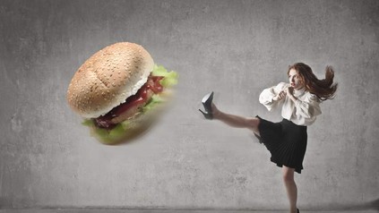 Eine Frau kickt einen großen Burger weg