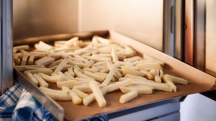 Tiefkühl-Pommes, die in den Ofen geschoben werden