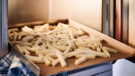 Tiefkühl-Pommes, die in den Ofen geschoben werden
