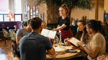 Gruppe im restaurant mit Kellnerin, die die Speisekarte reicht