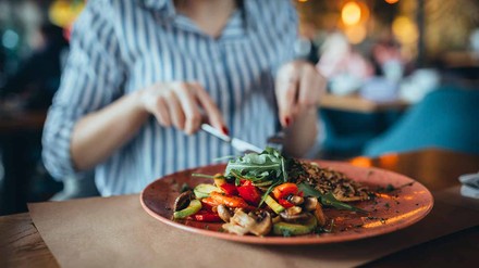 Frau schneidet vegetarisches Gericht in einem Restaurant