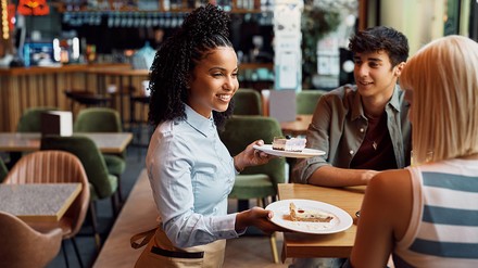 Kellnerin serviert Gästen Kuchen