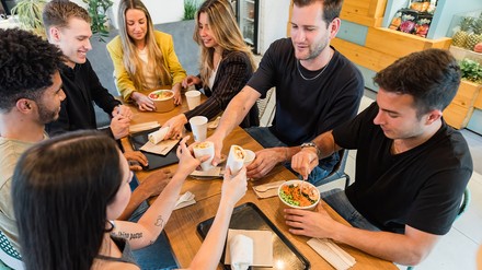 Ein Teller mit Gemüsesalat und eine weibliche Hand mit einem Stück brt