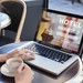 Frau bucht ein Hotelzimmer an ihrem Laptop und trinkt dabei einen Kaffee