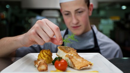Azubi, der ein Gericht verfeinert