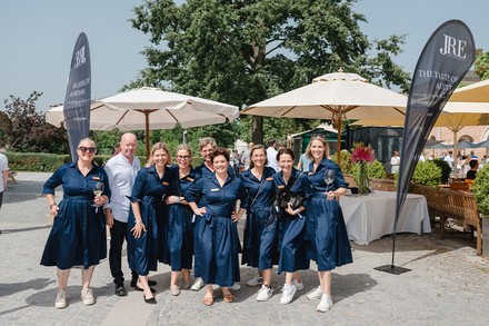 Einige der „starken“ Gastgeberinnen, alle im blauen Kleid zwischen zwei JRE Fahnen