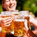 Vier Menschen stoßen mit Bierkrügen an