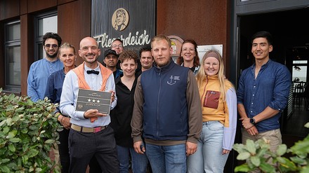 Das Team des Fliegerdeich Hotels mit einem Drei-Sterne-Schild