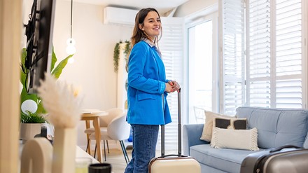 Junge Frau mit Koffer in einer Ferienunterkunft