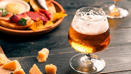 Ein Glas Bier mit einigen Delikatessen im Hintergrund