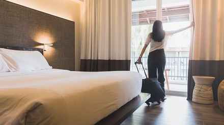 Frau steht am Fenster eines Hotelzimmers