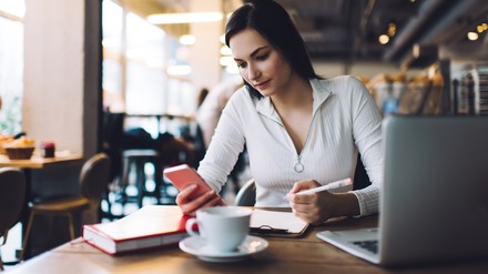 Junge Frau arbeitet Remote im Café
