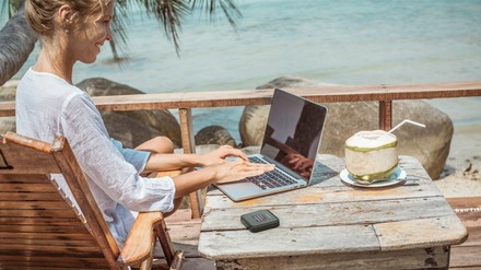Urlauberin mit Laptop am Strand