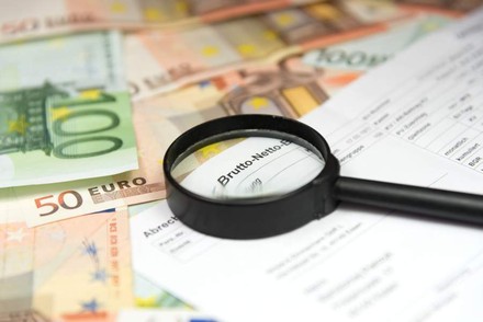 Eine Abrechnung und eine Lupe liegen auf mehreren Geldscheinen
