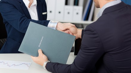 Zwei Menschen schütteln sich beim Bewerbungsgespräch die Hände