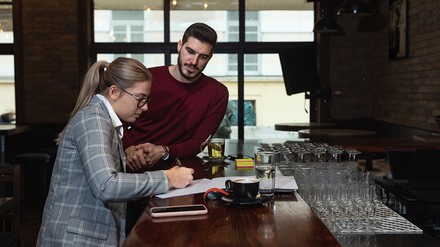 Mann und Frau besprechen am Tresen eines Restaurants Arbeitsschutzregeln