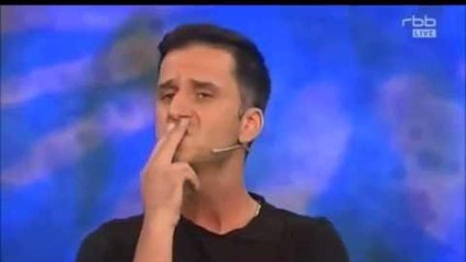 Mann hält sich zwei Finger vor den Mund