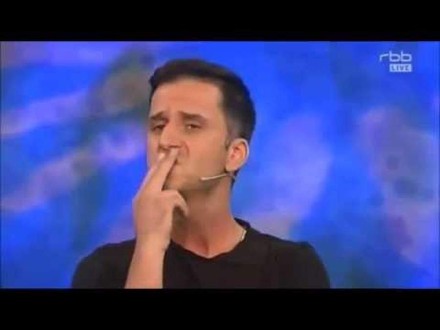 Mann hält sich zwei Finger vor den Mund