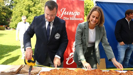 Der oberste Rekordrichter Olaf Kuchenbecker und Isabelle Junge, Nachhaltigkeitskoordinatorin der Konditorei Junge, nehmen die finale Messung des Gebäcks vor