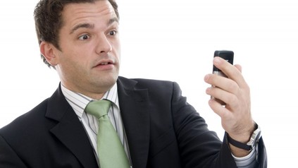 Geschäftsmann sieht erstaunt auf sein Handy