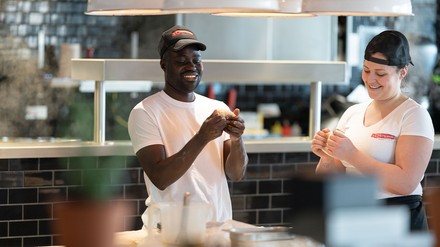 Zwei Mitarbeiter machen gemeinsam Pizza