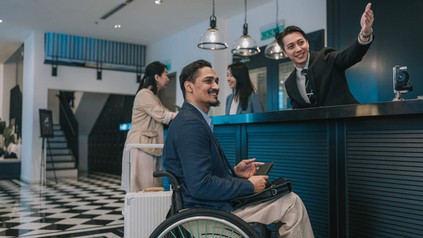 Mann im Rollstuhl an der Hotelrezeption