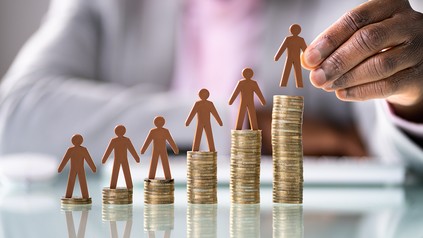 sechs immer größer werdende Türme aus Geld, auf ihnen drauf steht jeweils ein Holzmännchen.