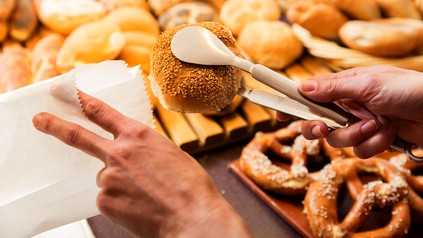 Bäcker packt Sesambrötchen ein