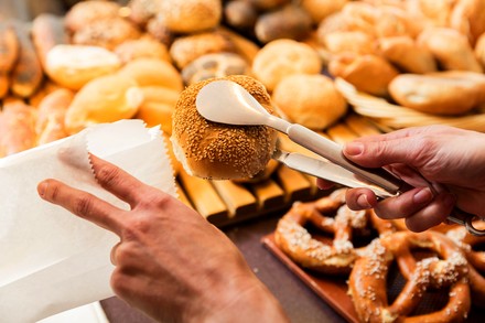 Bäcker packt Sesambrötchen ein