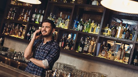 Barkeeper hinter dem Tresen telefoniert