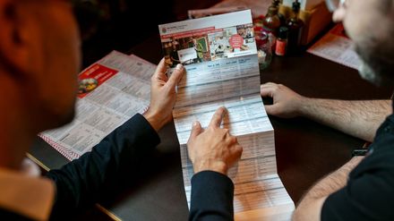 Zwei Männer schauen auf einen Vokalbelflyer